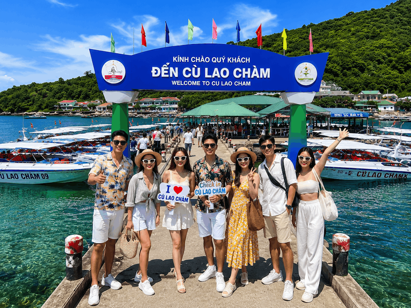 Du khách check in trên cầu cảng Cù Lao Chàm với nước biển trong xanh và cano neo đậu phía sau