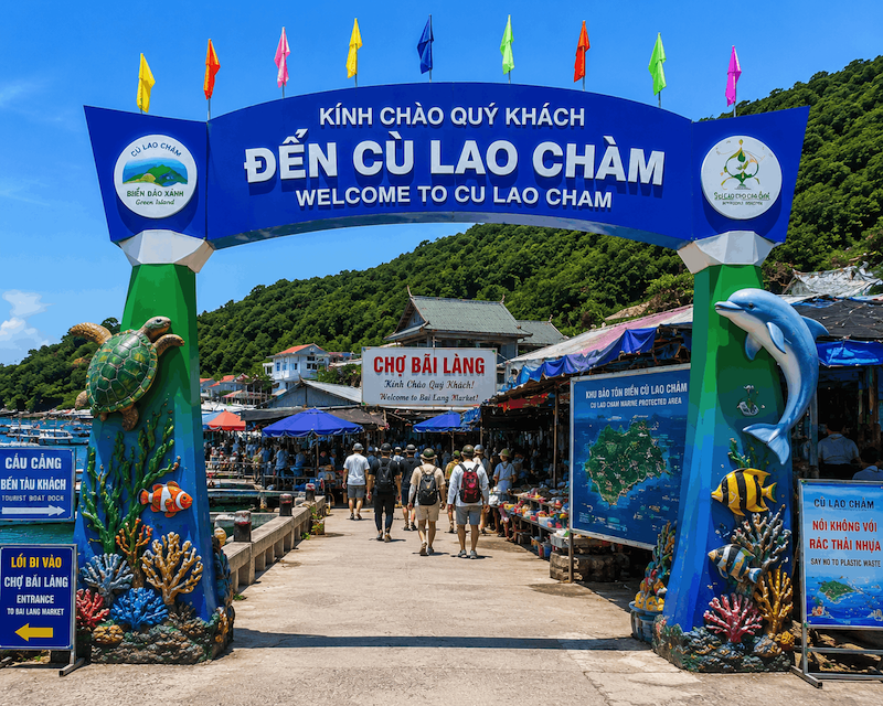 Cổng chào xanh tại cầu cảng Cù Lao Chàm với hình ảnh sinh vật biển và lối đi dẫn vào khu chợ Bãi Làng